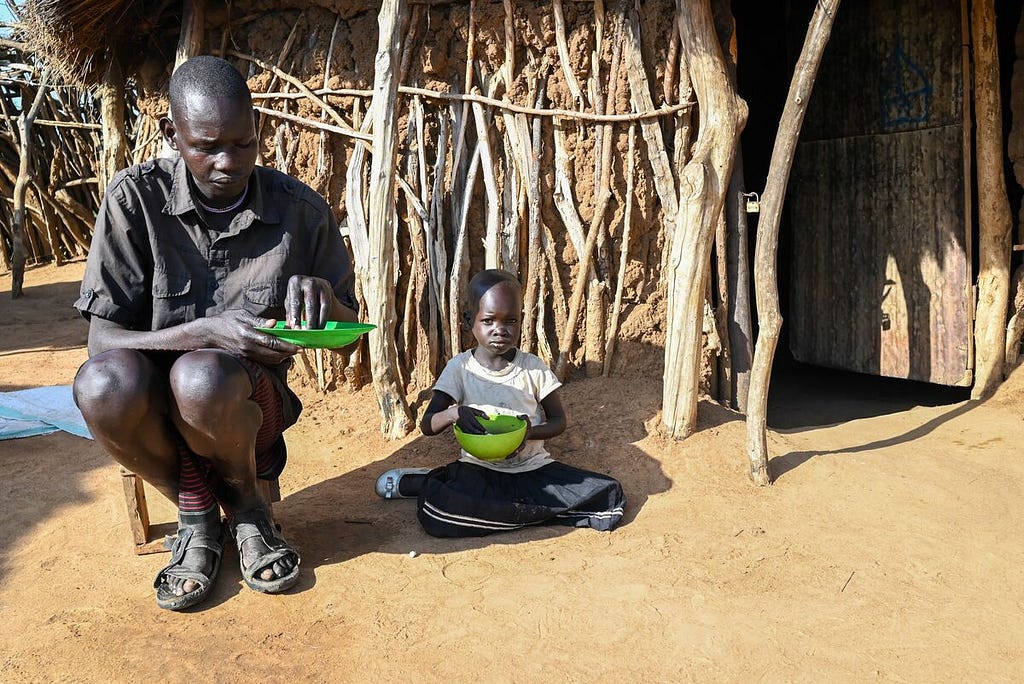 Eli and ius daughter Alice sit outside their home eating a meal.