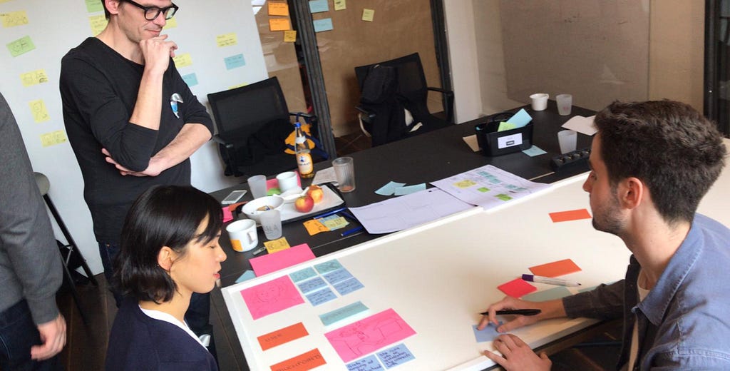 Three people at a table, one facilitatinig a workshop exercise.