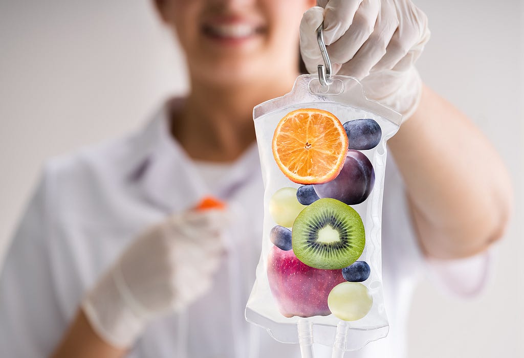 A woman dressed in white showing a serum including different types of fruits and vitamins