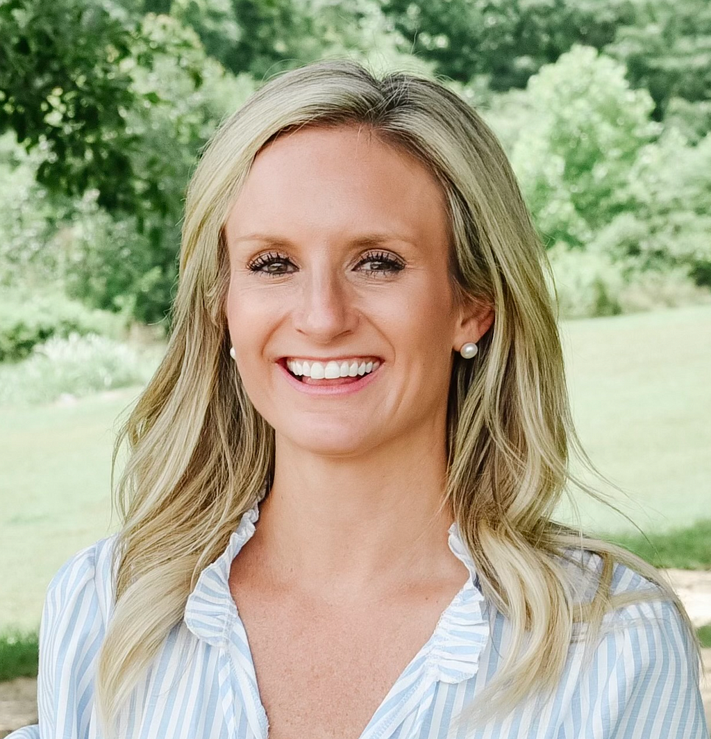 Headshot of Dr. Lindsey Calcutt. Dr. Calcutt is smiling in a outdoor setting wearing the Incora earrings.