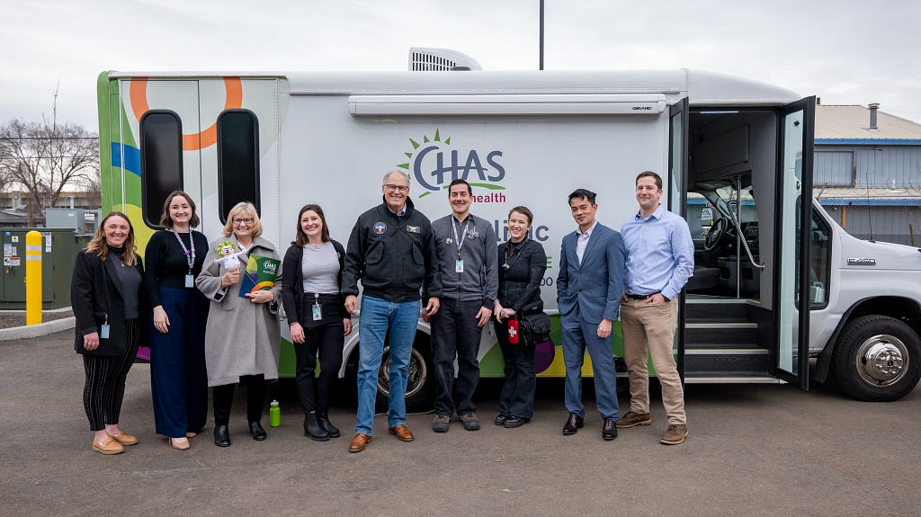 Gov. Jay Inslee and a group of mental health responders take a picture by their mobile medical unit van.