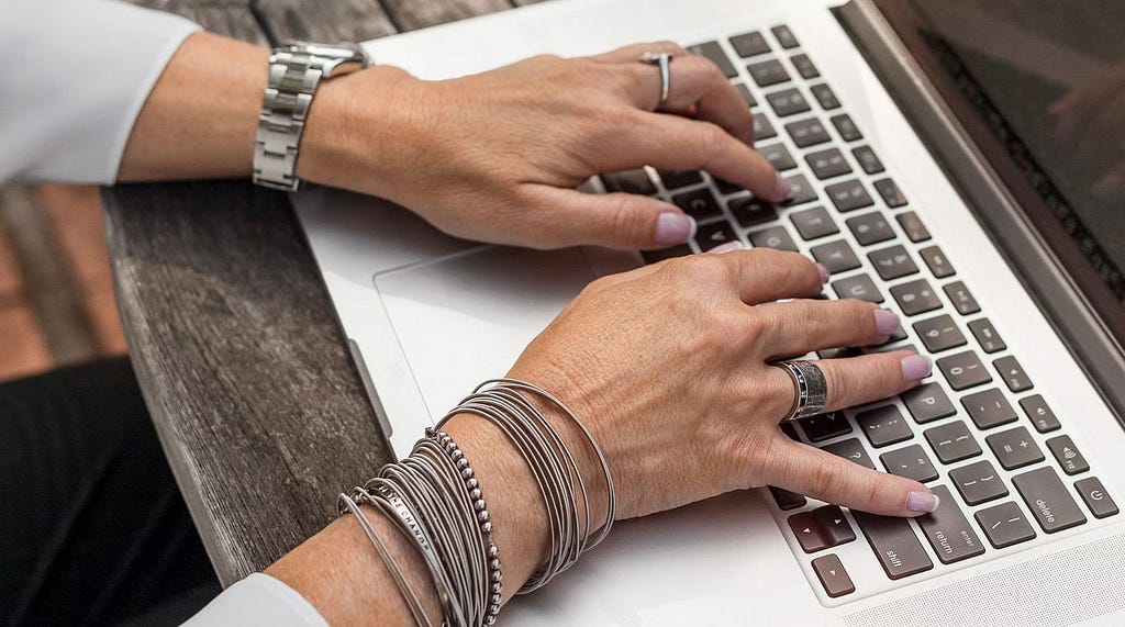 Hands typing on an Apple laptop keyboard