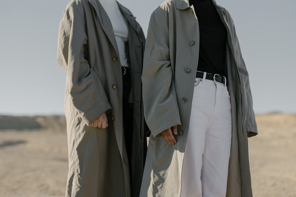 two persons in oversized trench coats