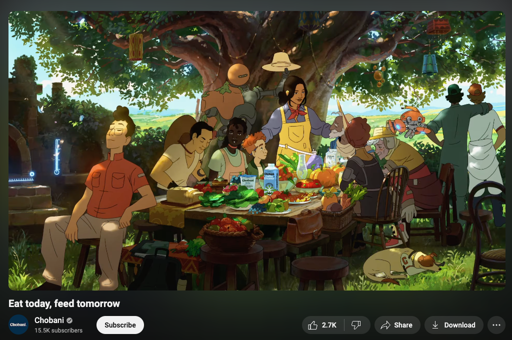 A screenshot from the Chobani youtube channel featuring the “Eat today, Feed tomorrow” campaign. The still from the video shows a diverse group of people gathering around a communal dinner table under a big tree to share a meal. There’s lots of greenery, futuristic robots living in harmony with people, and Chobani products.