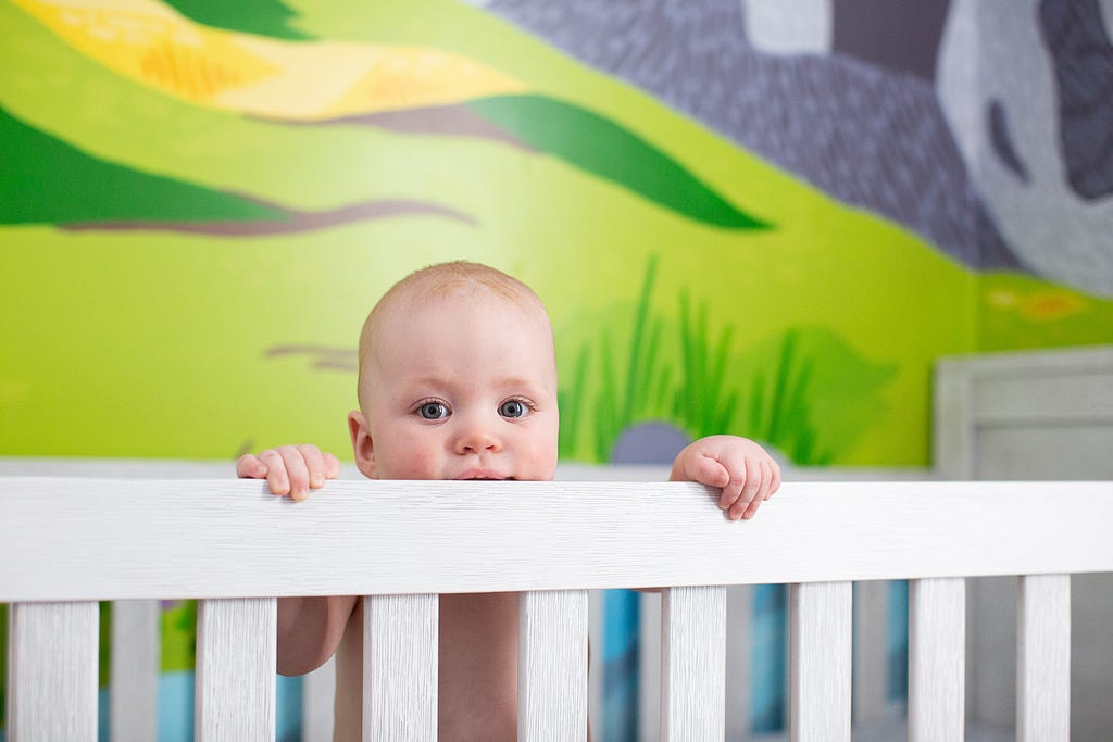 baby peeking out over crib railing