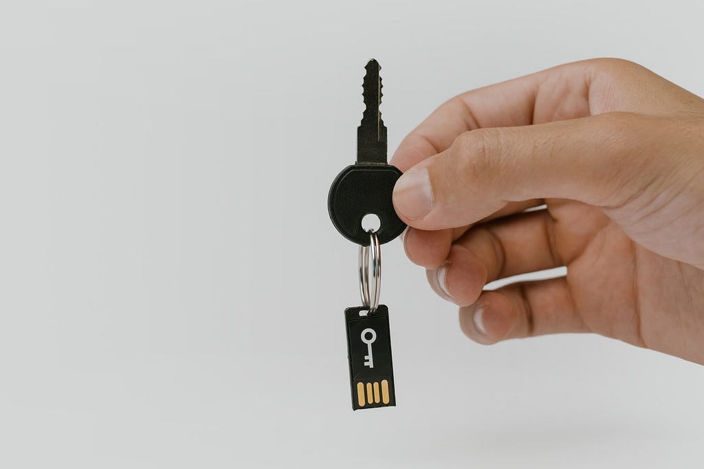 Hand  holds a USB hardware security key on a keychain.
