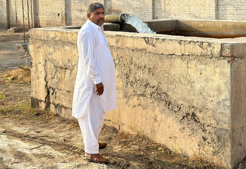 A man stands in front of a well.