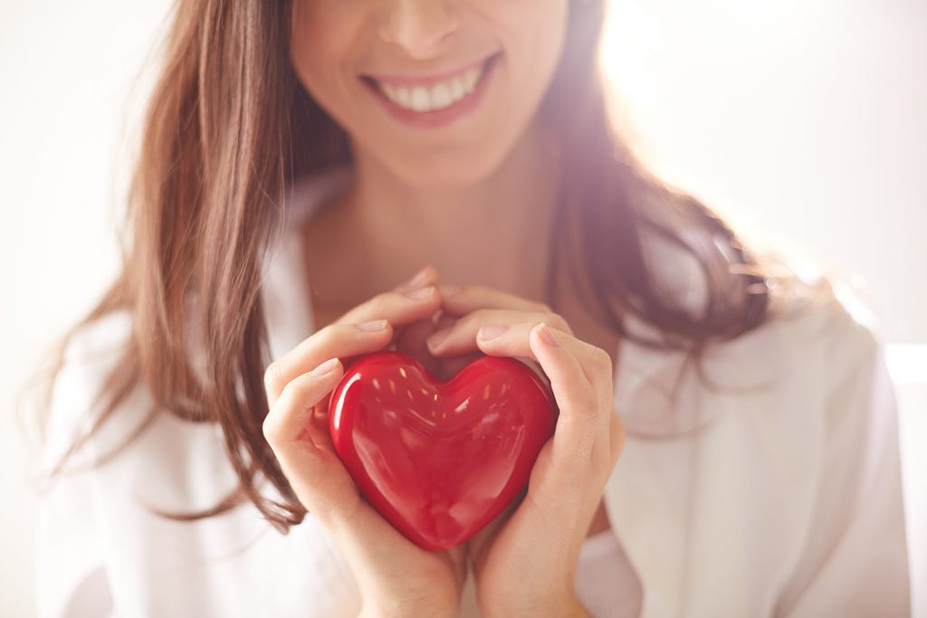 woman holding a red heart in front of her