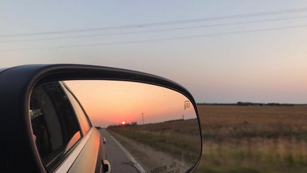Car mirror reflecting the sunrise