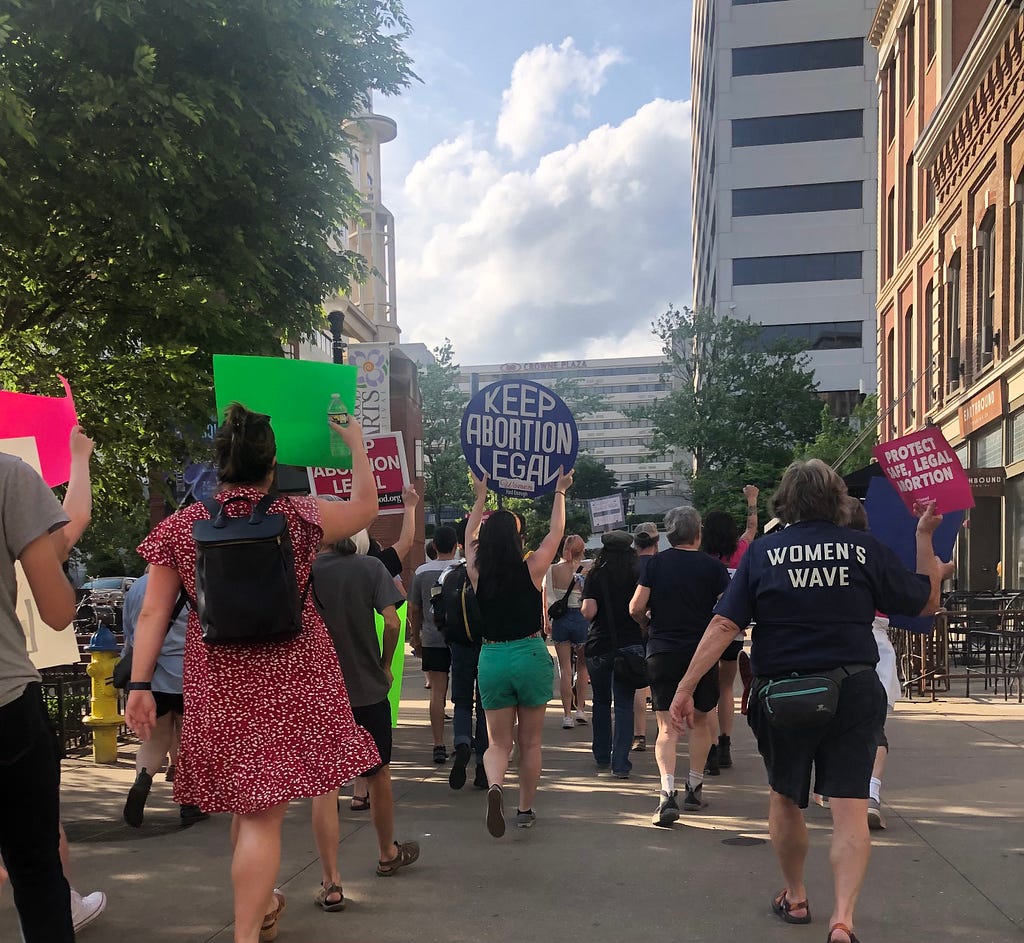 Someone holding a ‘Keep Abortion Legal’ sign at a protest in a city