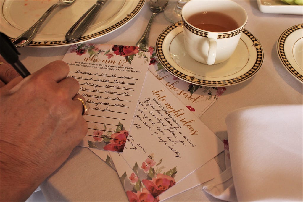 Flower Pink and White Cards With Cursive Writing on Them Next To Cup of Tea