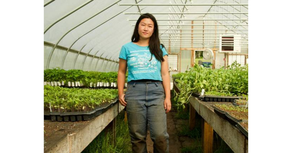 Christina Chan poses in a high tunnel surrounded by seedlings.