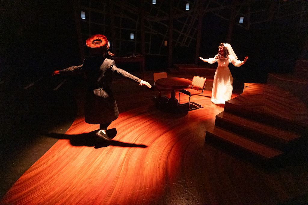 In a photograph from THE WANDERERS, two actors dance onstage in Hasidic dress — the man wears a long black coat and a fur hat, while the woman wears a modest wedding gown.