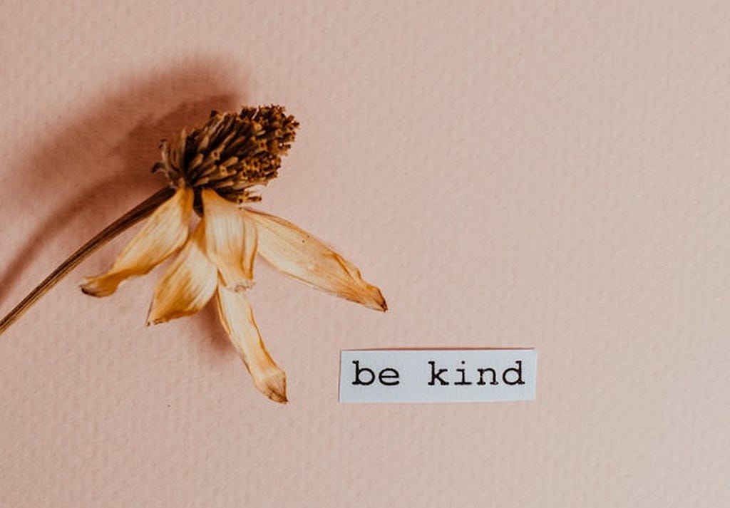 a flower and a piece of paper that says be kind.