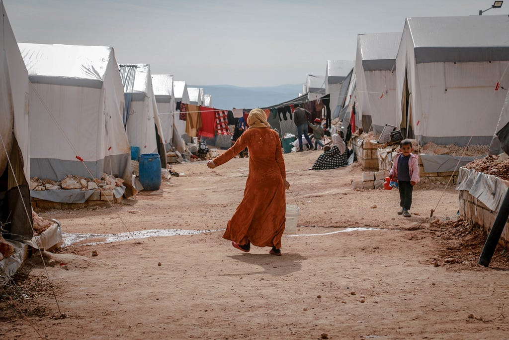 A woman walking in a refugee camp in Idlib, Syria