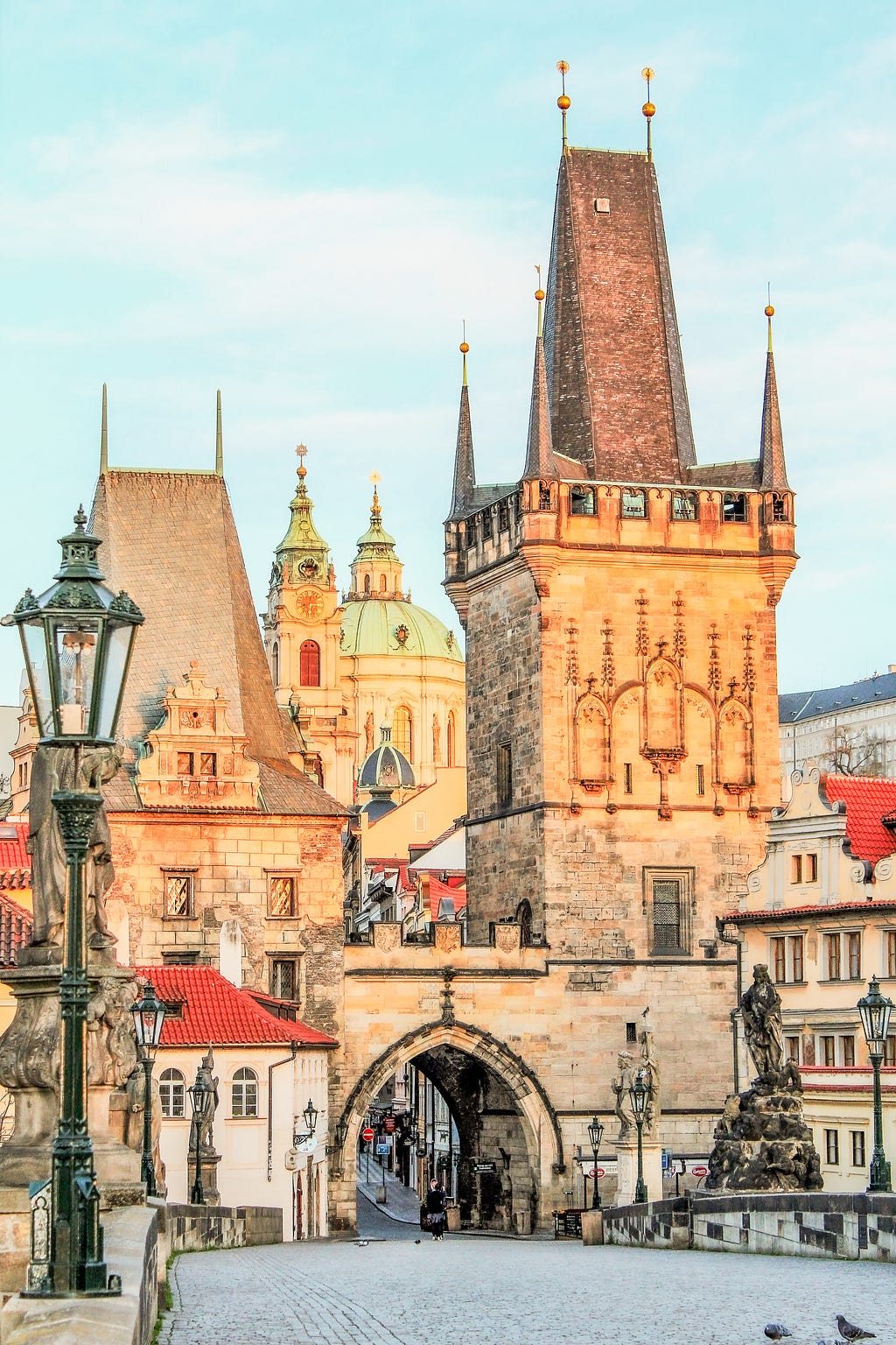 Charles Bridge in Prague with Tower and spires of churches under glow of sunrise