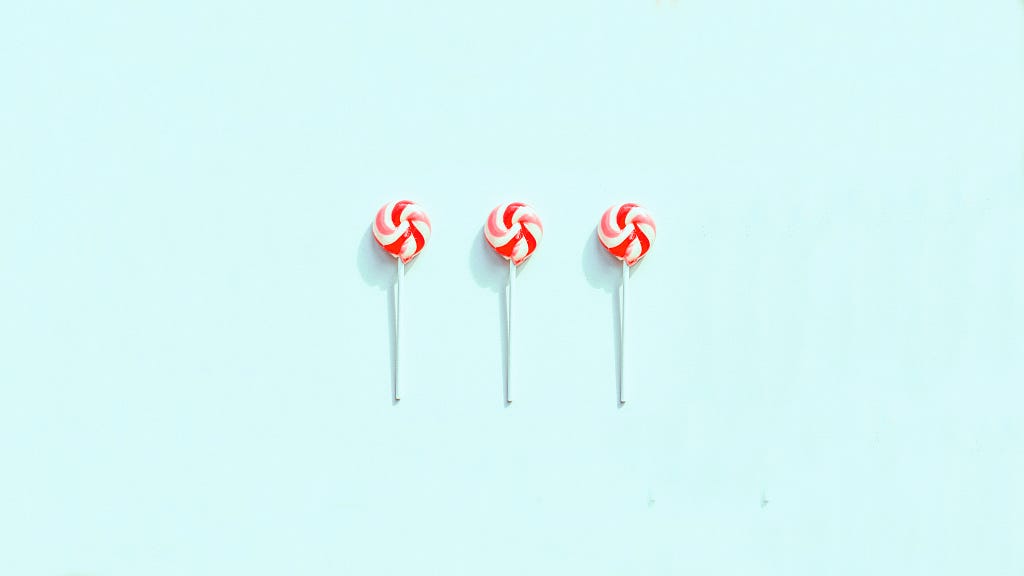 Three red and pink lollipops against a sky blue background.