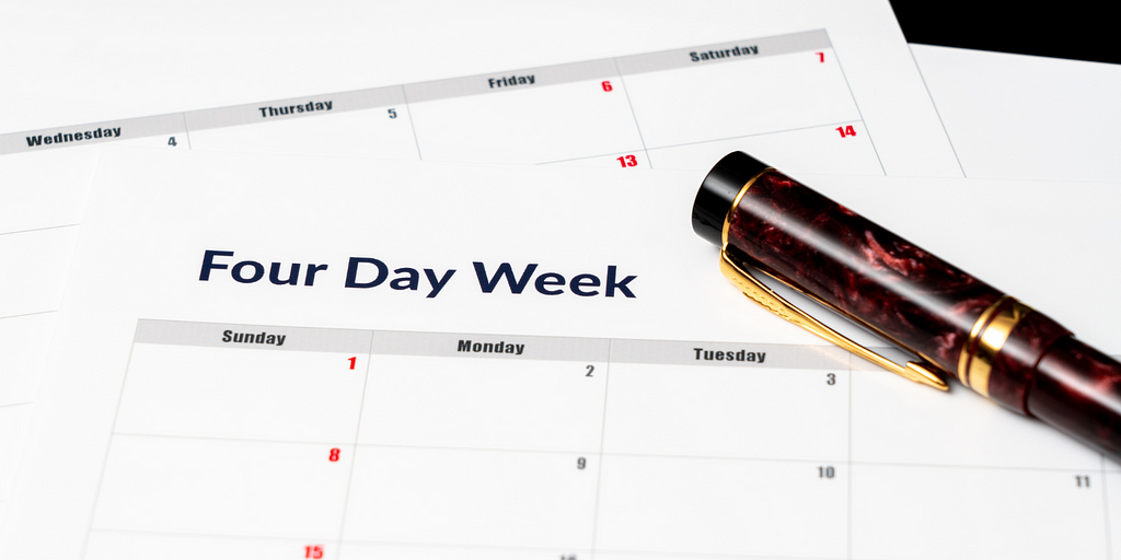 A red marbled pen sits on top of a calendar with the heading “Four Day Week.”