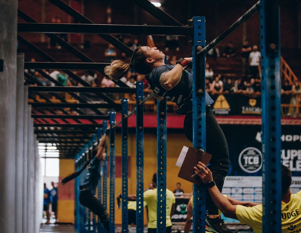 Ilustração de uma mulher realizando um movimento chamado Chest to bar (peito na barra) durante uma competição