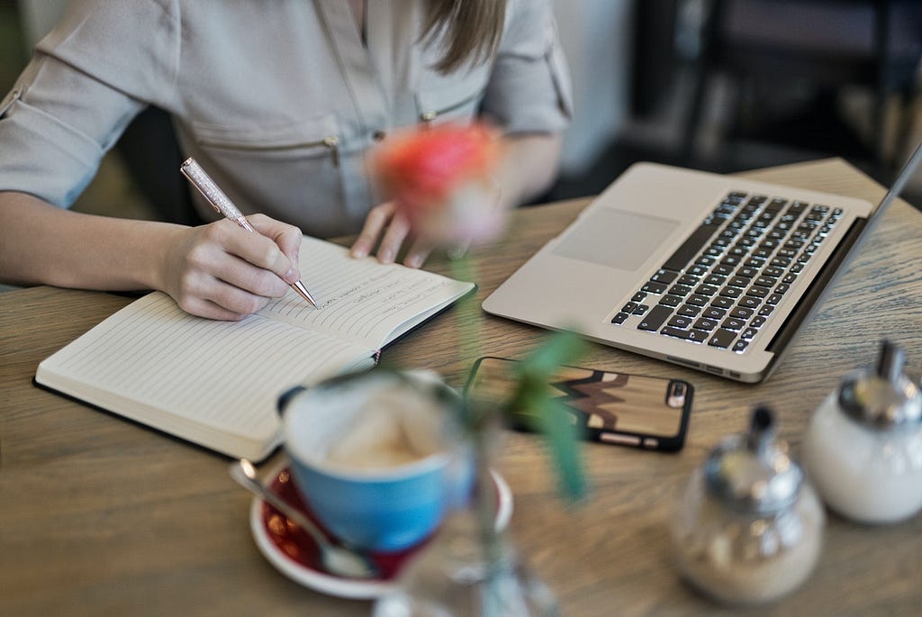 A woman writing her journal on the table.