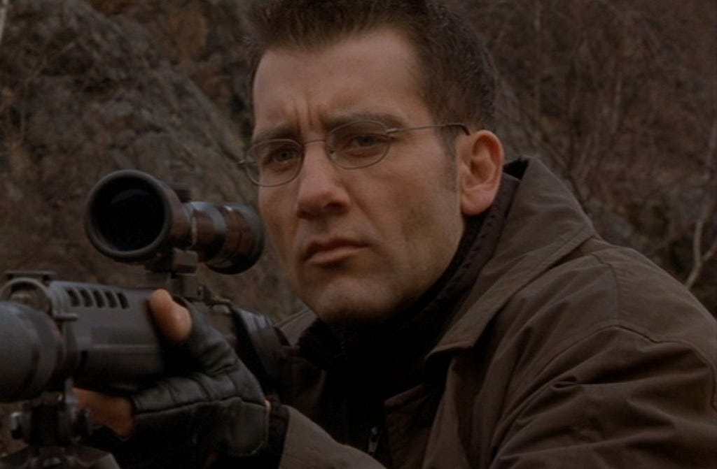 Clive Owen prepares to use his scoped rifle