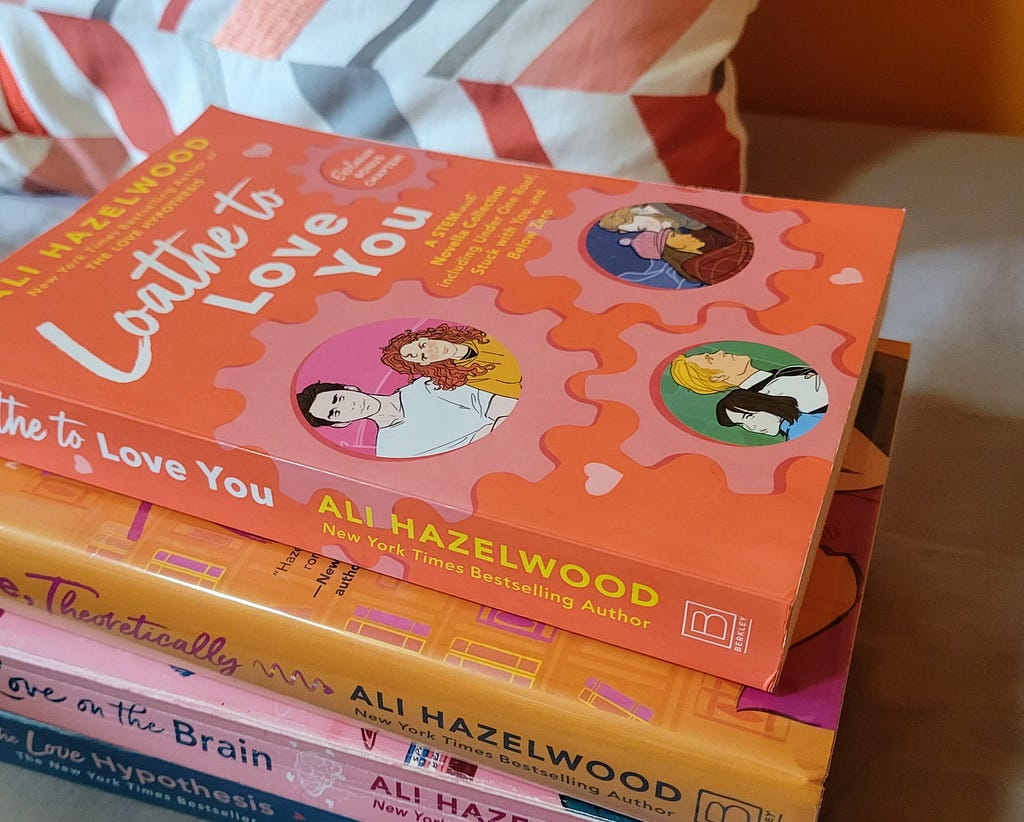 A stack of books by Ali Hazelwood, with the novella collection Loathe to Love You featured on top