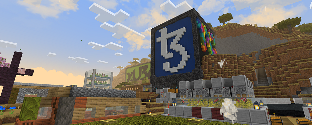 A Minecraft survival server with a large Tezos logo build, redstone mechanisms, and hillside farms, captured at sunset.
