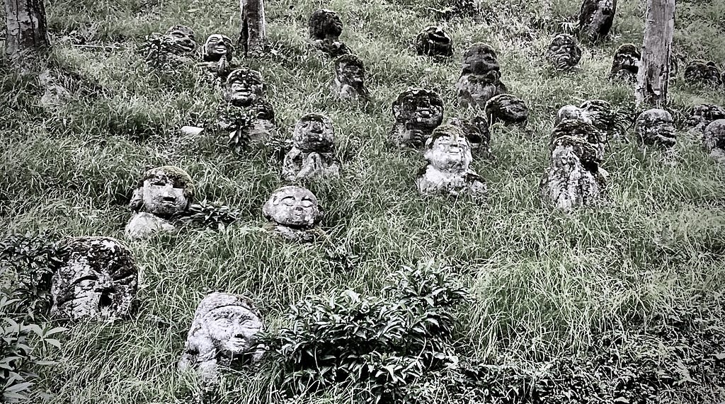 Several stone Buddhist statuettes called Jizo (geez-oh) on a grassy slope in Kyoto, Japan.