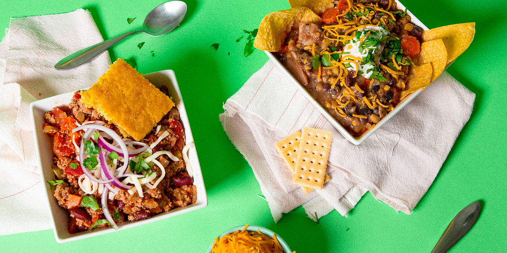 Two bowls of chili on a green background