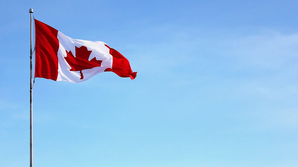 The image shows the flag of Canada waving on flag pole.