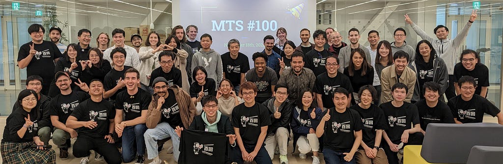 A group photo with several dozen people taken after MTS #100. Most are wearing the t-shirt made for the event.