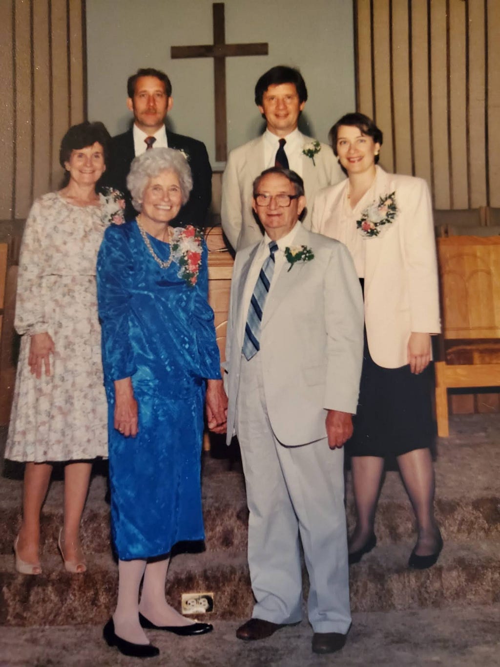 family photo, elders in front, four grown children in back, in church for wedding anniversary