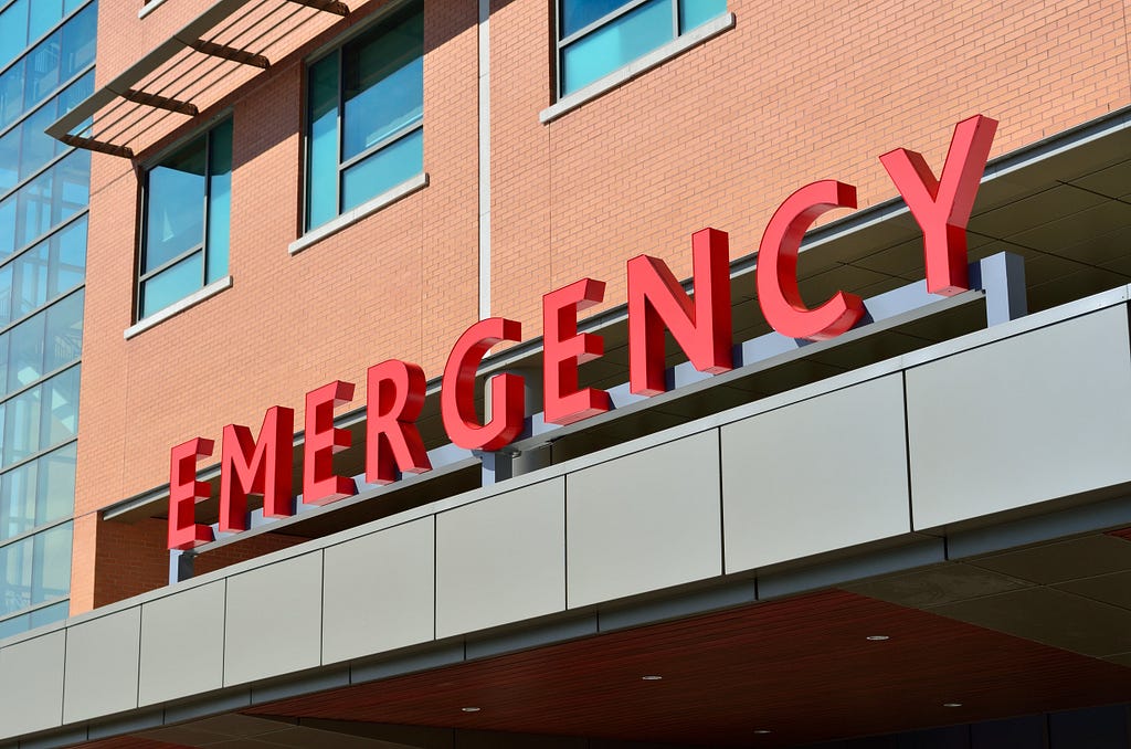 An emergency room outdoor signage with the word “EMERGENCY” in red capital letters