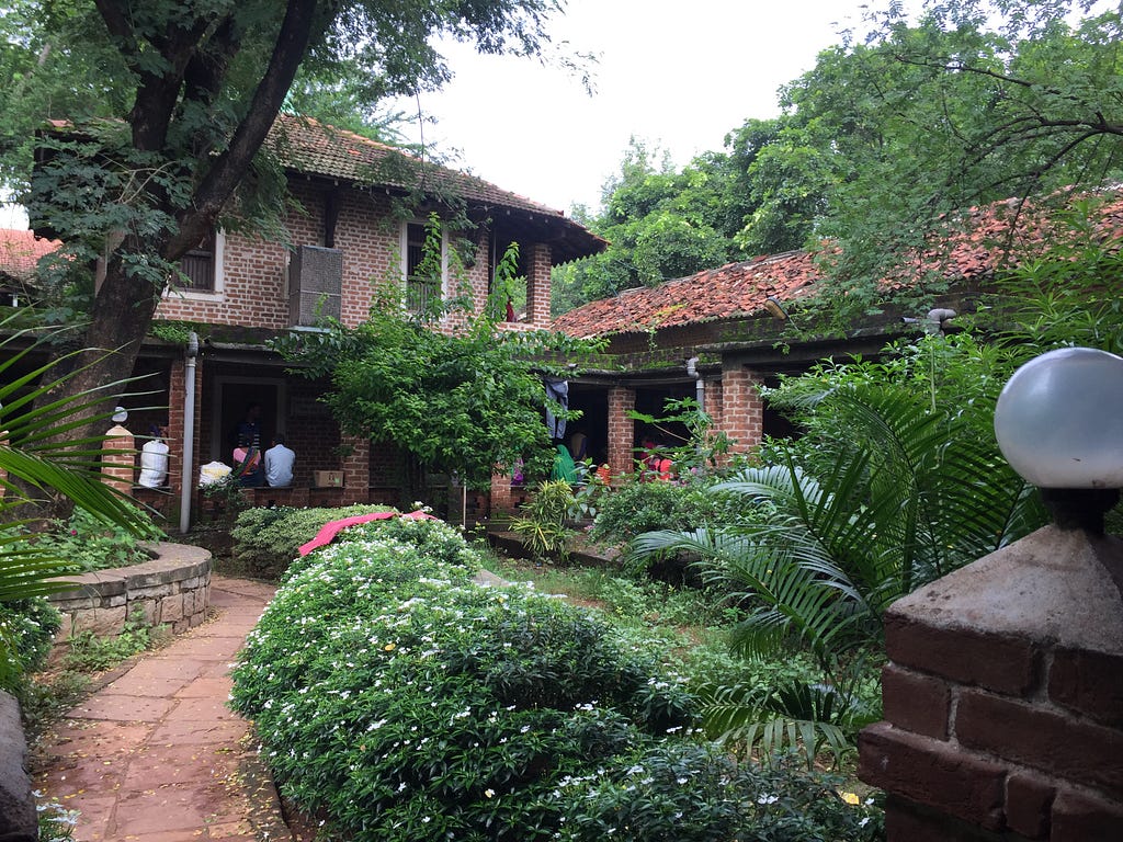 An open air hospital with two floors and a courtyard in the middle with lush vegetation.