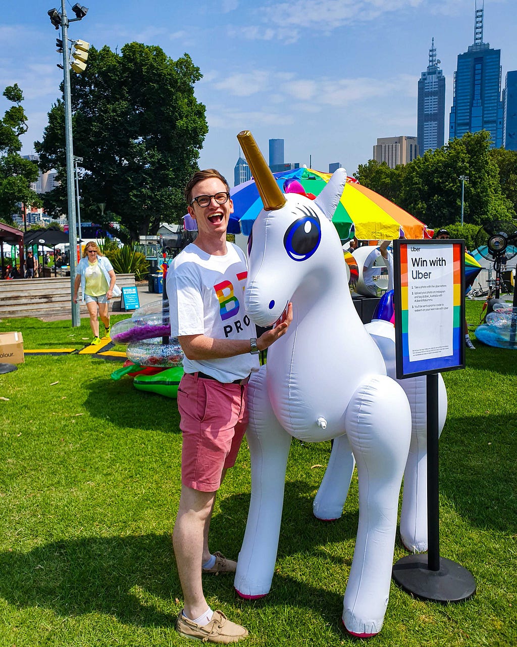The author next to a large white inflatable unicorn, with a cheeky grin on their face.