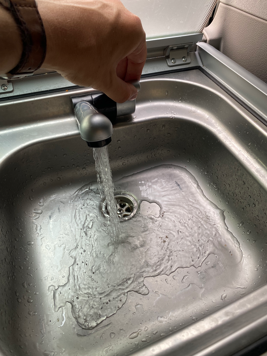 Water faucet in Volkswagen California kitchen sink with flowing water after fixing issues by replacing water pump.