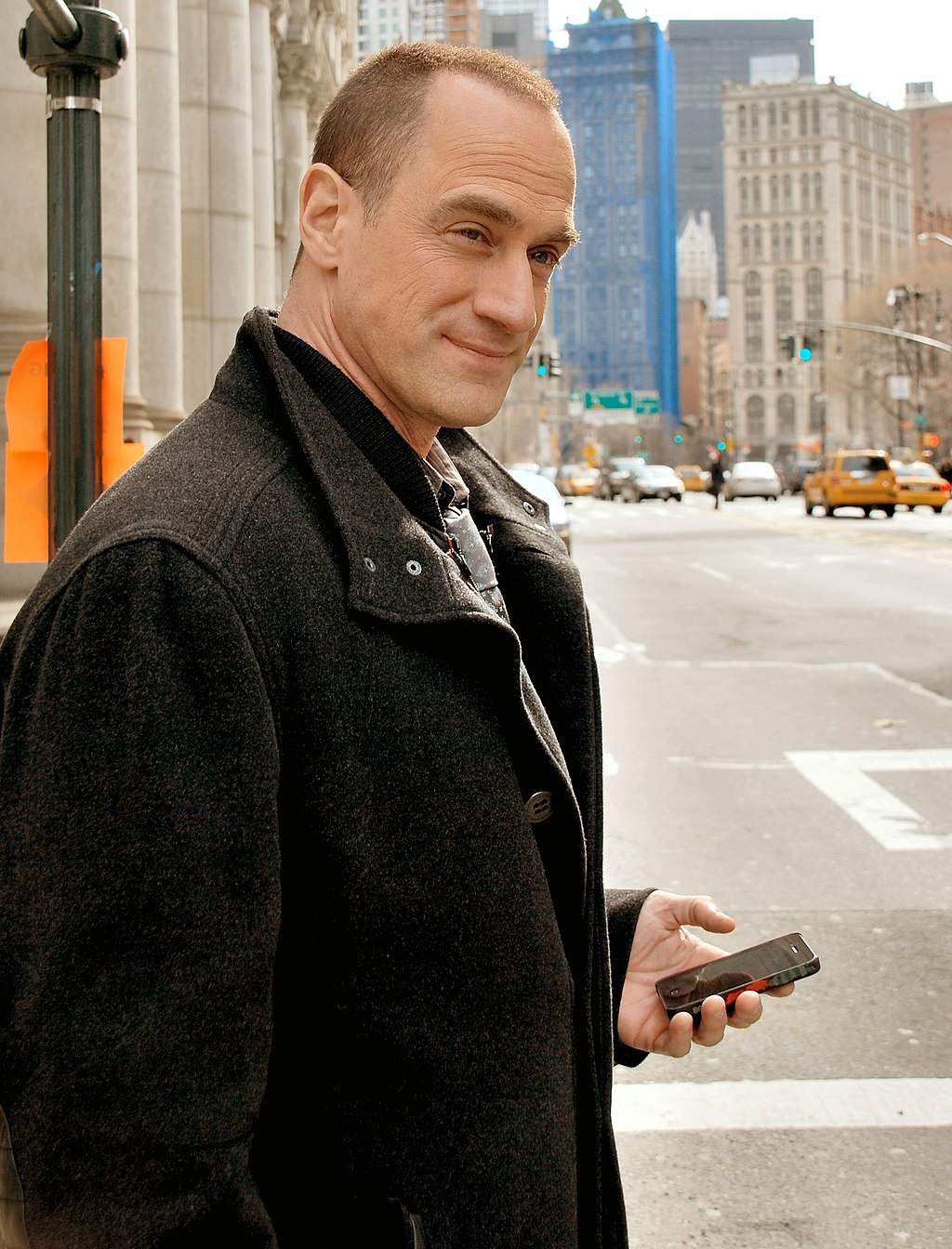 Actor Christopher Meloni dressed as his Detective Stabler character, wearing a long black overcoat.