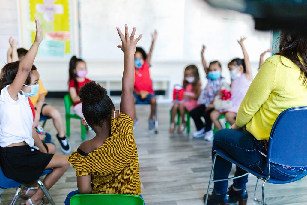Students raising their hands during an interactive discussion with the teacher