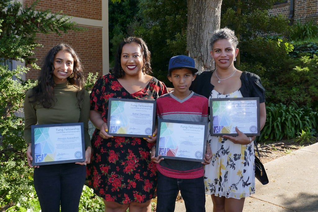 Rahel and family pose outside with their plaques.
