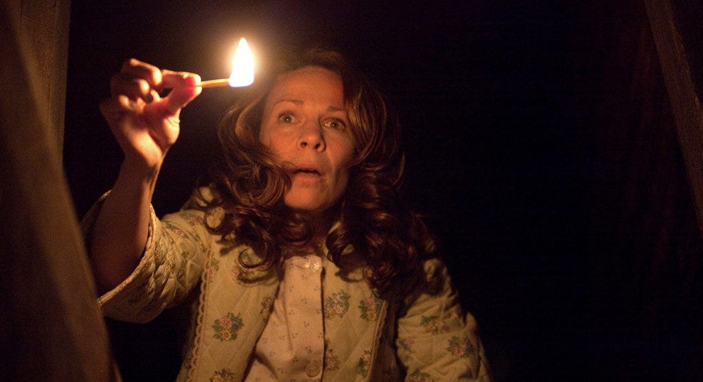 A woman holds a lit match in the dark