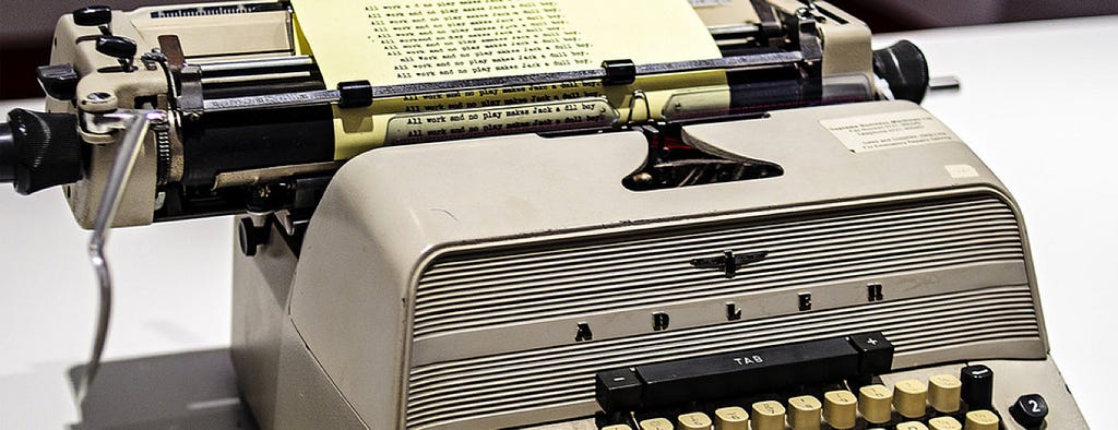 Close up photograph of a vintage typewriter with the phrase “All work and no play makes Jack a dull boy” types repeatedly.