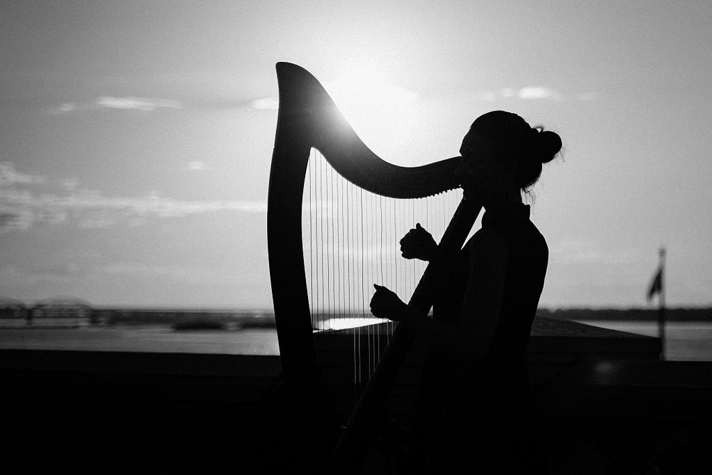 Silhouette of a woman playing a folk harp