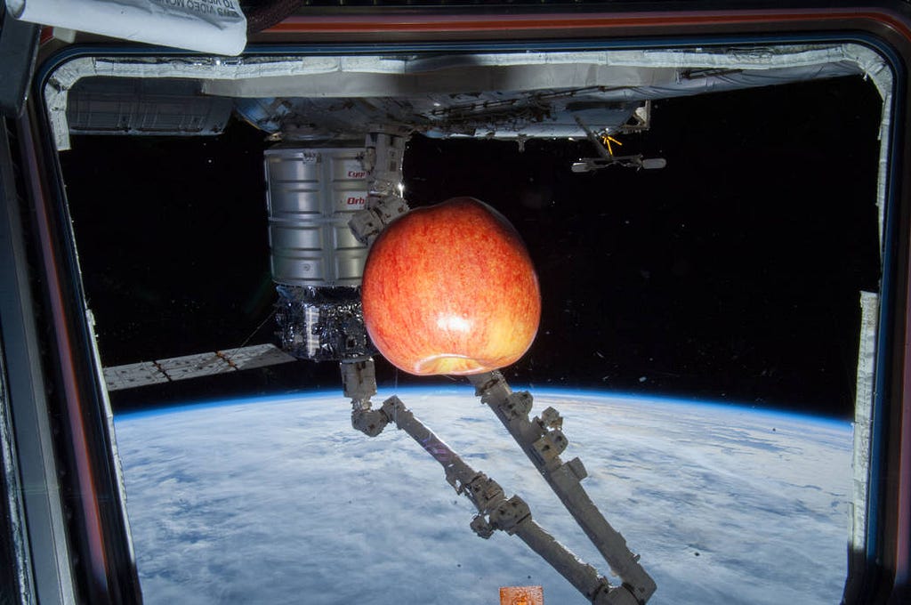 Photo of an apple floating, or rather experiencing orbital momentum, in the ISS space station — image courtesy of NASA