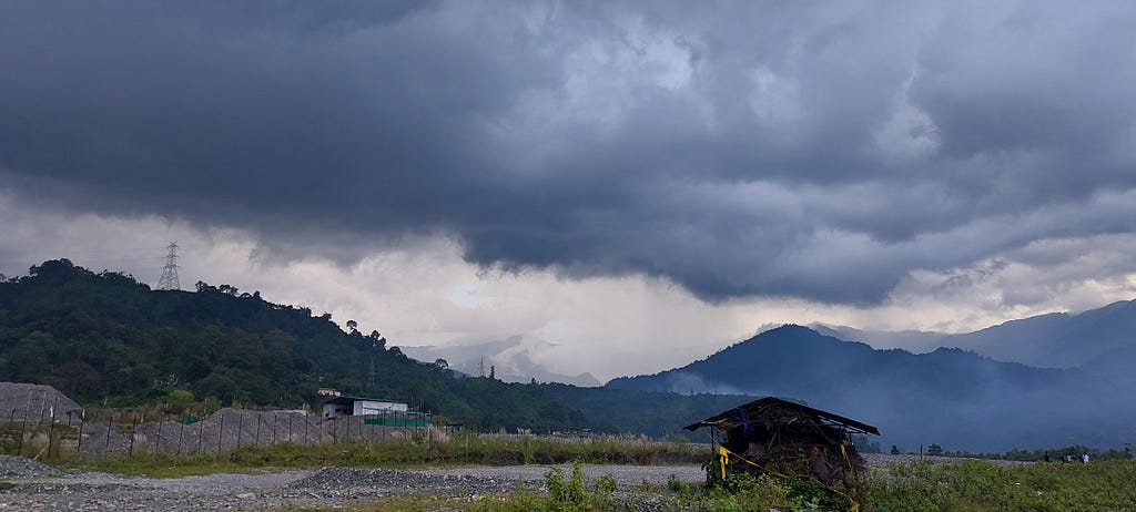 Cloudy sky with mountains and a hut beneath