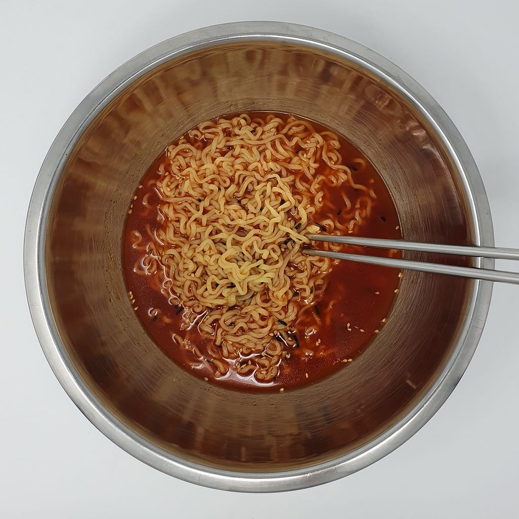 A finished bowl of Wicked Ramen (Yogoe Ramyeon) Shinsadong Naengcho-Myeon Flavor still in the bowl with chopsticks.