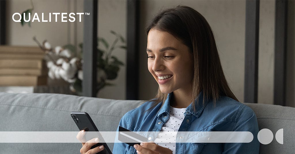 Qualitest. A girl holding a smartphone and a credit card with a smile.