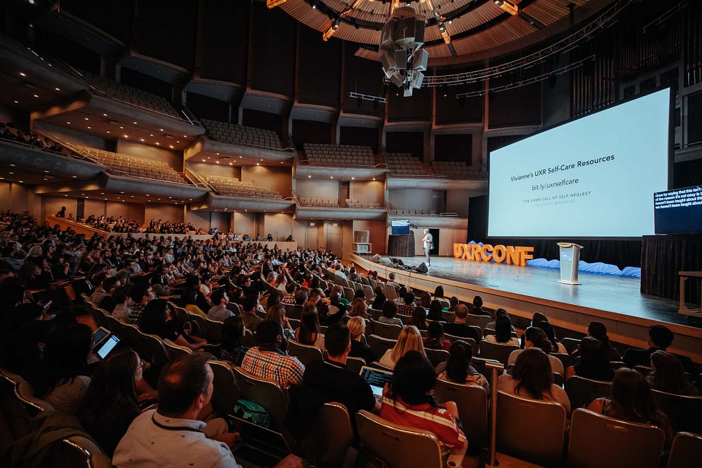 Vivianne Castillo speaking on-stage at Roy Thomson Hall at Strive: the UXR Conference