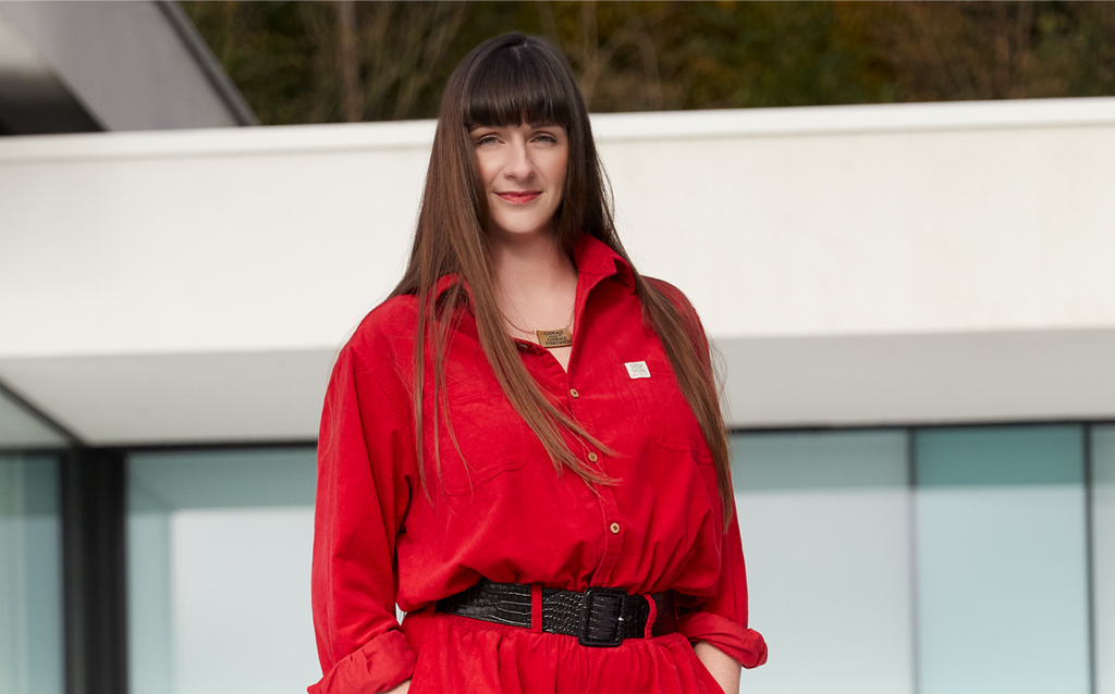 Laurens wears a red boiler suit in front of a beautiful whitebuilding