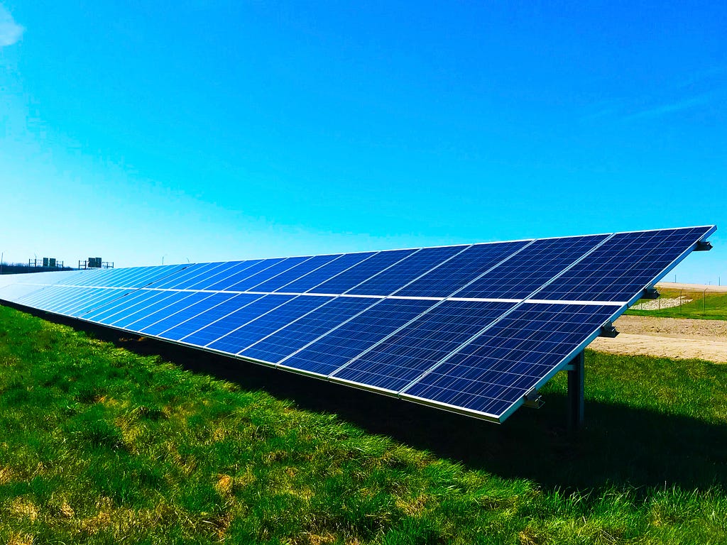 An array of solar panels in the field on bright sunny day.