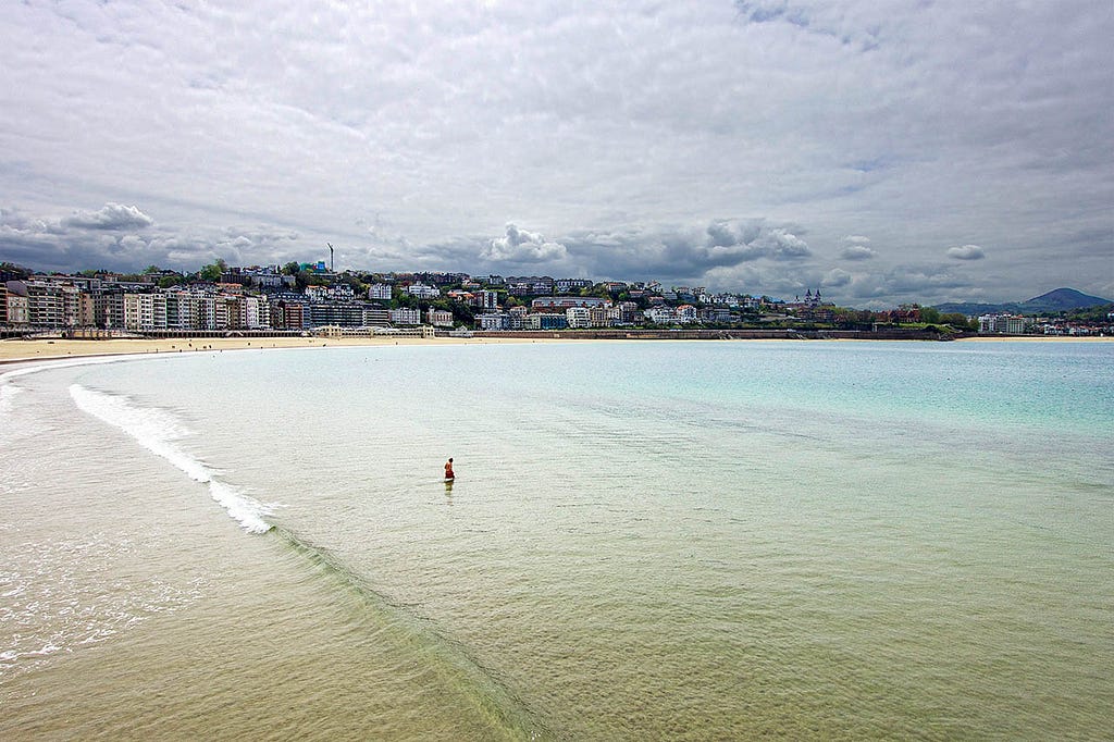 a single beach goer enjoys the surf